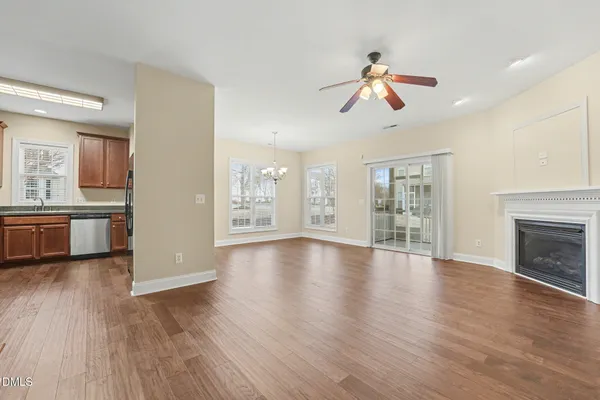 a view of a livingroom with wooden floor a ceiling fan and windows