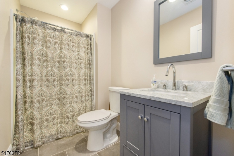 6 Elm Street, Unit 10 Madison, NJ 07940 - Photo 12 of 15 a bathroom with a granite countertop toilet a sink a mirror and a shower