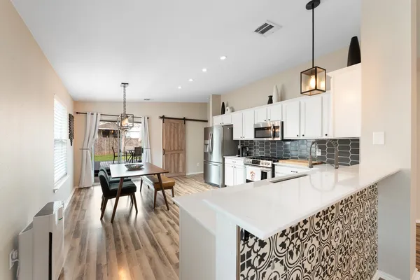 a kitchen with kitchen island granite countertop a stove a sink a refrigerator and white cabinets with wooden floor