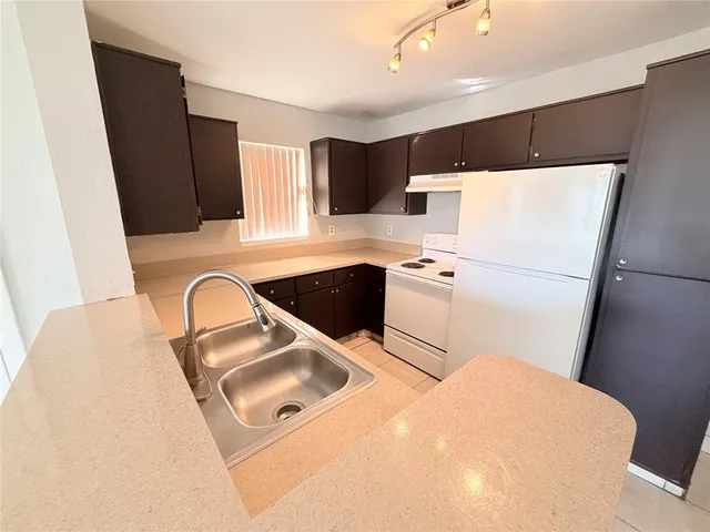 a white kitchen with sink a refrigerator and washer