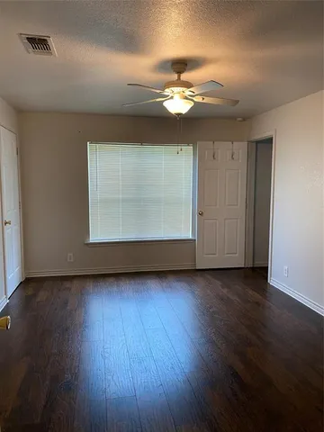 an empty room with wooden floor chandelier and windows