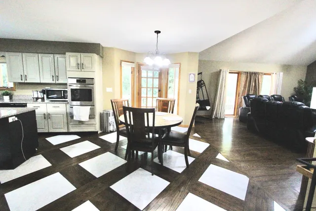 a dining room with wooden floor a chandelier a wooden table and chairs
