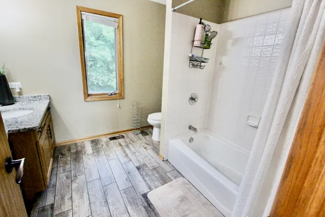 a bedroom with a bed wooden floor and window