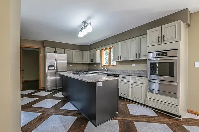 a kitchen with stainless steel appliances granite countertop a stove refrigerator and cabinets