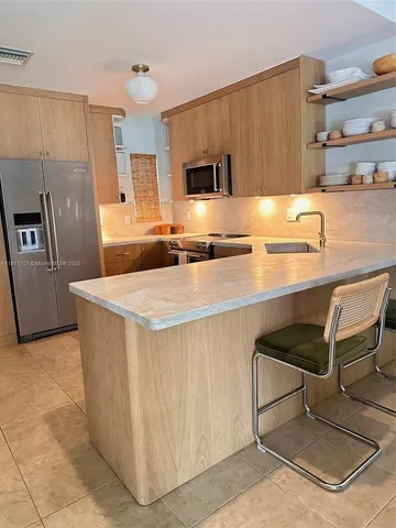 a kitchen with stainless steel appliances granite countertop a sink and a refrigerator