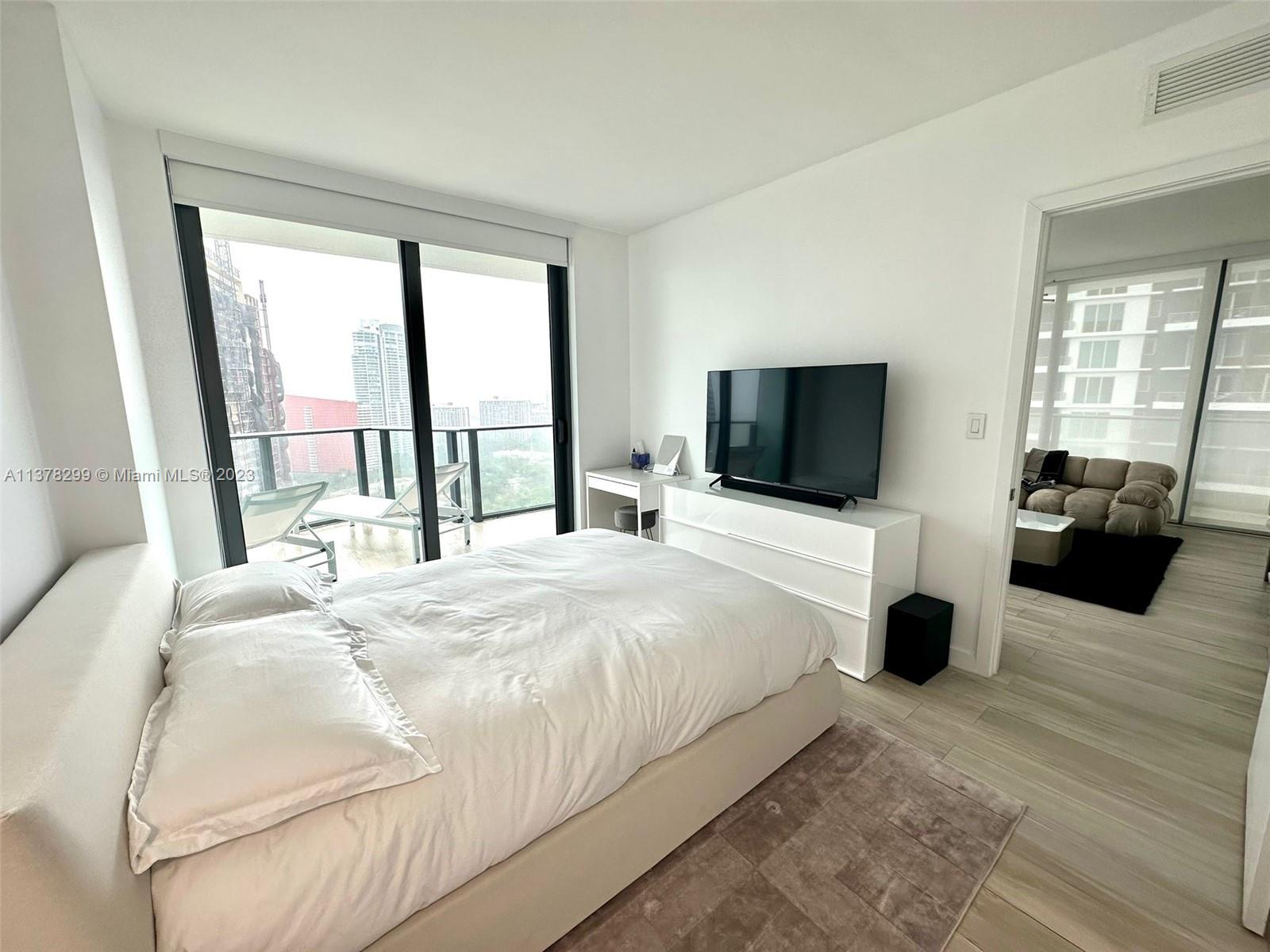 Brickell Miami, FL 33130 - Photo 12 of 17 a bedroom with a bed a large window and a flat tv screen