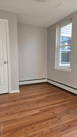 a view of an empty room and wooden floor and window