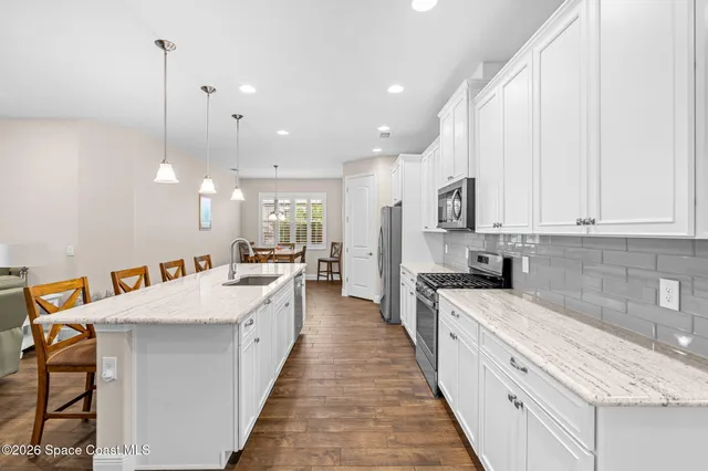 a large white kitchen with lots of counter space sink and cabinets
