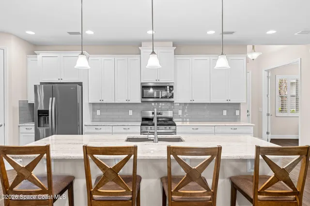 a kitchen with stainless steel appliances granite countertop a kitchen island a stove a sink a dining table and chairs with wooden floor