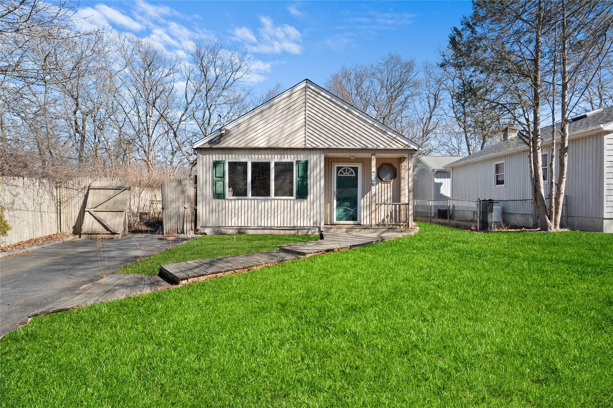 View of front of property featuring aphalt driveway, a gate, fence, and a front lawn