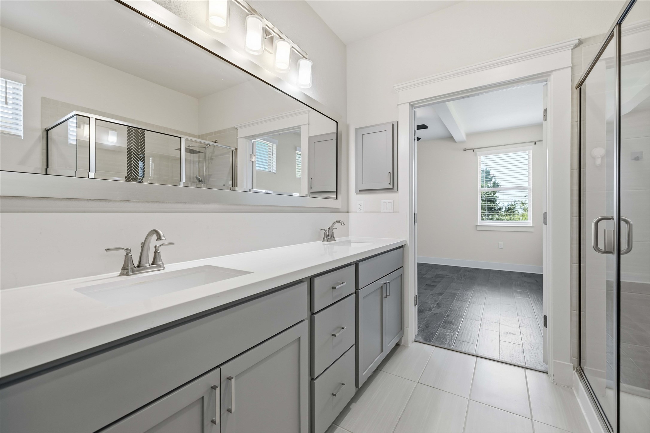 1722 Rowdy Loop, Unit 7 Leander, TX 78641 - Photo 19 of 37 Spacious bathroom featuring a double vanity with modern fixtures, ample storage, and a sleek glass-enclosed shower, leading into a bright room with large windows.