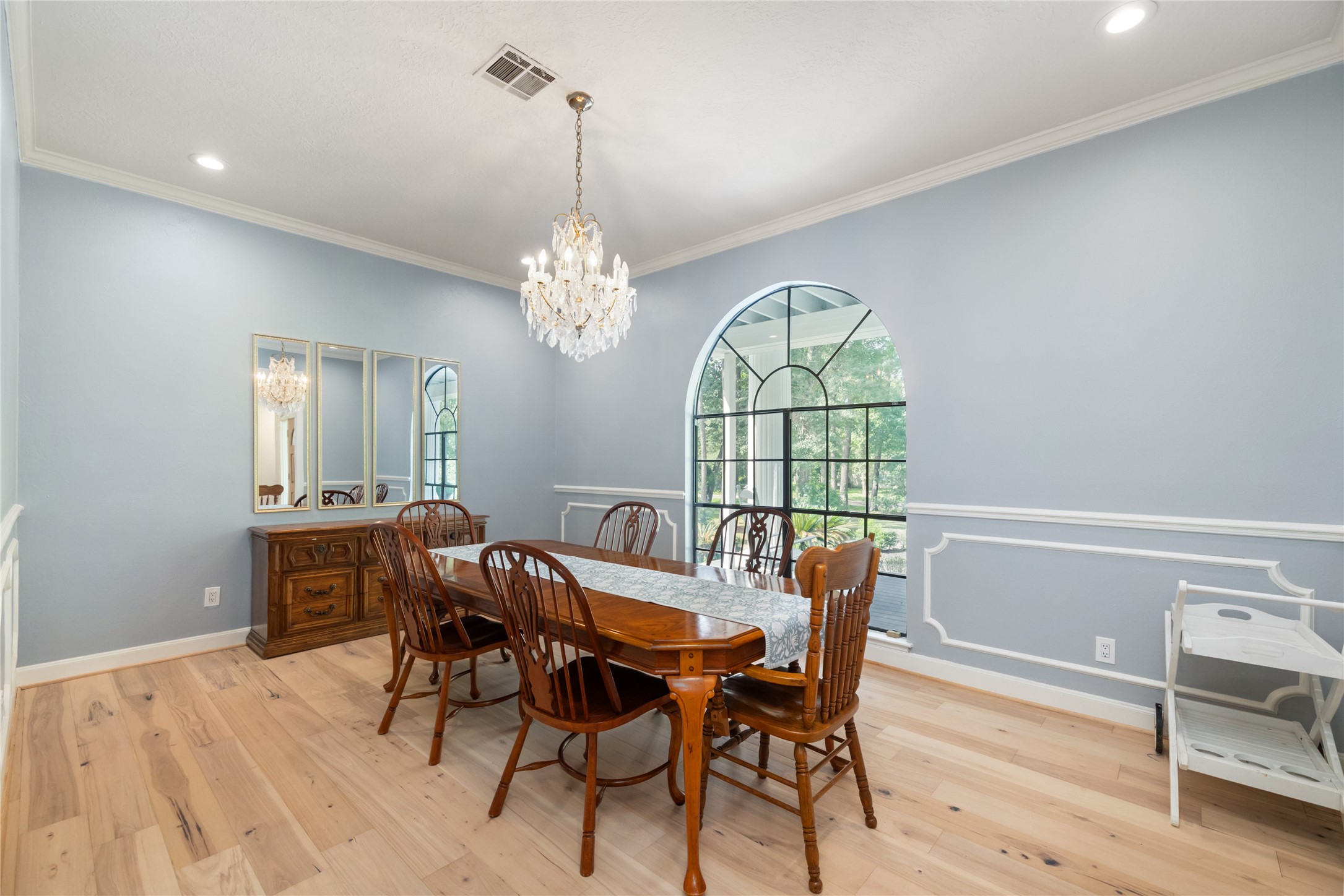 17003 Creeksouth Road Houston, TX 77068 - Photo 12 of 49 Bathed in natural light from a large window, this formal dining room features classic crown molding, chair railing, and an elegant chandelier—offering a refined space for memorable gatherings.