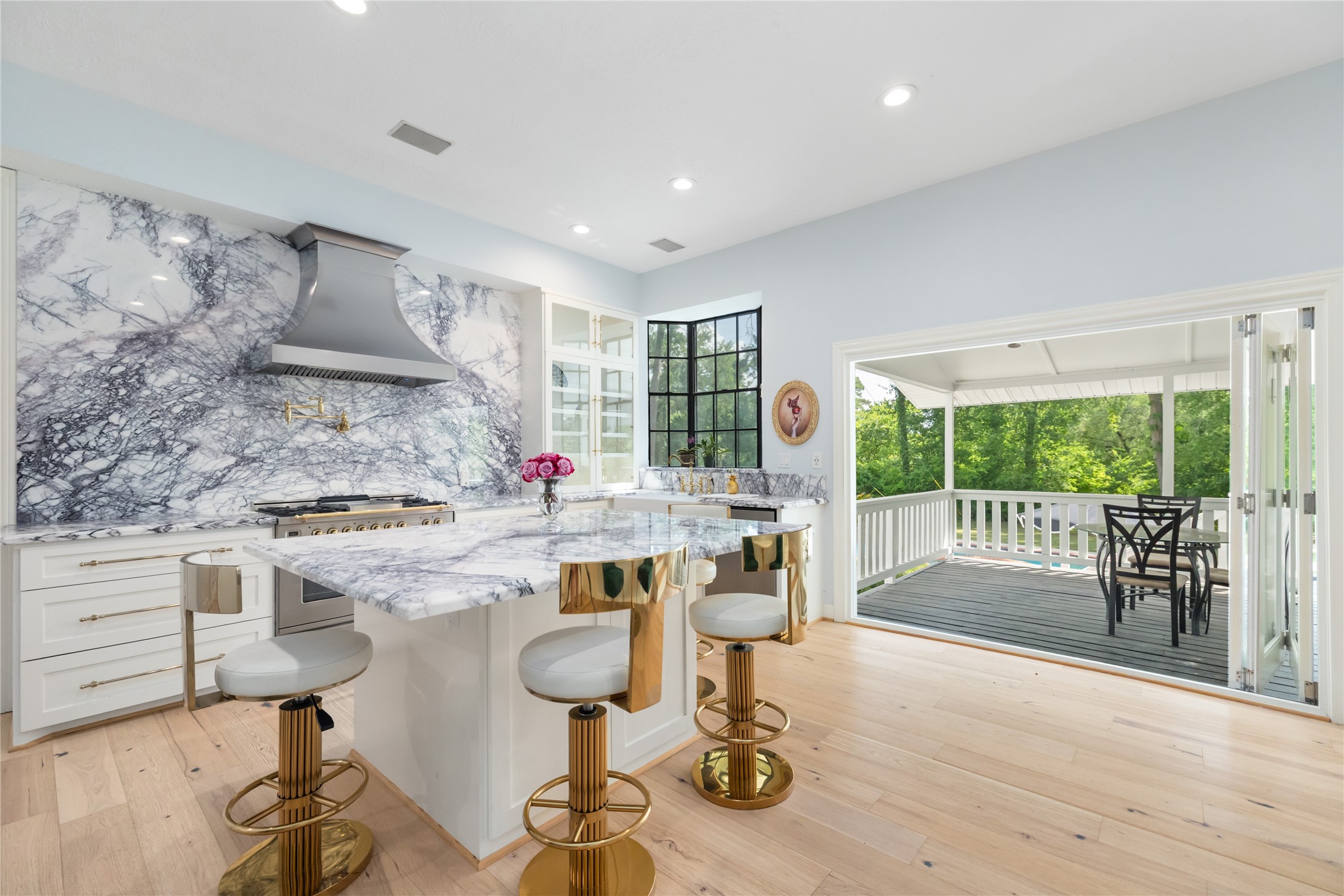 17003 Creeksouth Road Houston, TX 77068 - Photo 20 of 49 Bright and open, this stunning kitchen features marble countertops (installed in 2022) and backsplash, a spacious center island, and large windows that flood the space with natural light. Thoughtful details include a pots-and-pans drawer for easy organization—and most impressively, an accordion door that seamlessly opens a wall to the covered deck, blending indoor and outdoor living effortlessly.