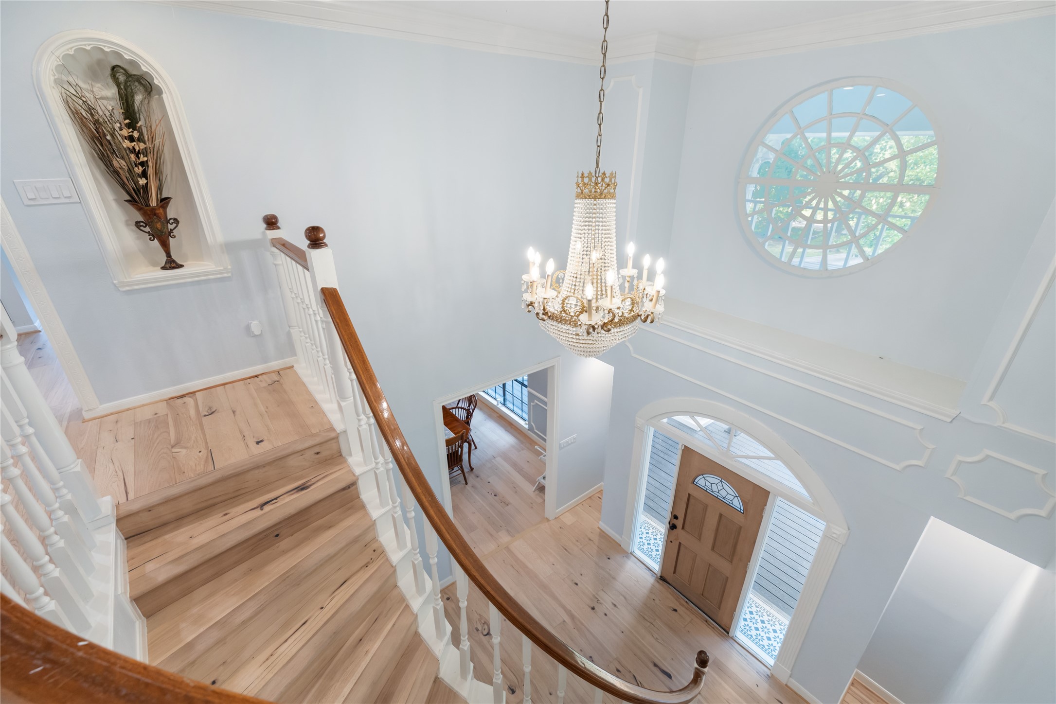 17003 Creeksouth Road Houston, TX 77068 - Photo 25 of 49 A sweeping curved staircase, illuminated by abundant natural light, serves as the centerpiece of this stunning architectural design. A striking chandelier and expansive windows complement the soaring ceilings, creating a bright, open, and airy ambiance that captivates at every turn.