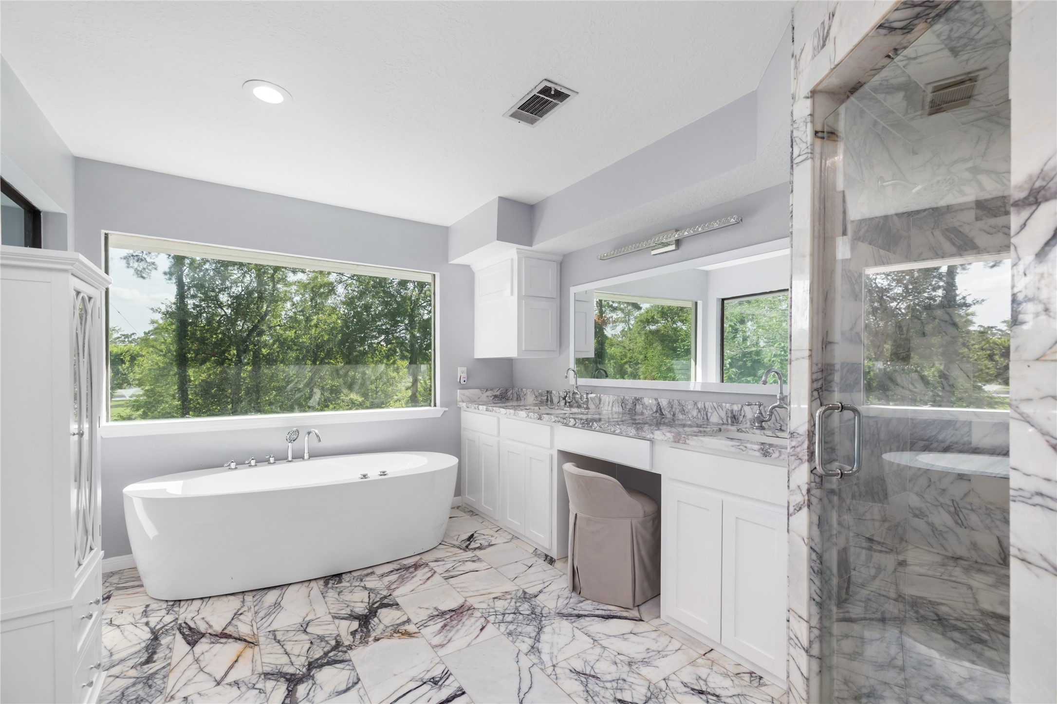 17003 Creeksouth Road Houston, TX 77068 - Photo 29 of 49 This luxurious bathroom, updated in 2022, features elegant marble tile throughout, a spacious soaking tub, and a walk-in shower. Large windows fill the space with natural light, while ample vanity area offers both function and style for daily routines.