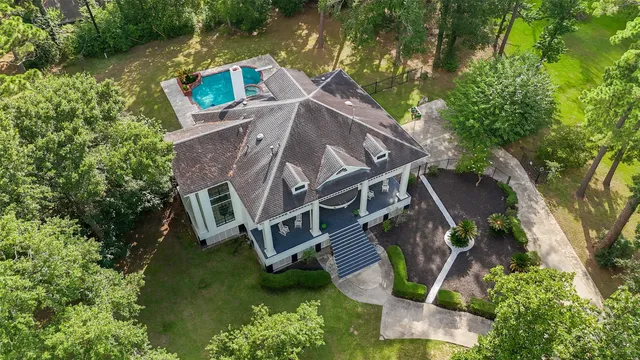 an aerial view of a house with garden space and trees all around