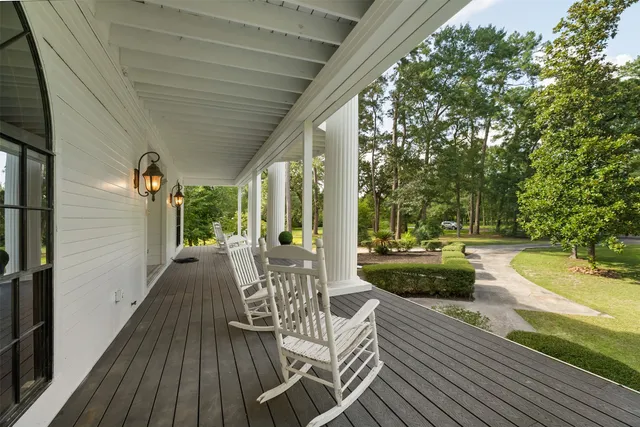 a view of a patio with couches table and chairs and potted plants with wooden floor and fence