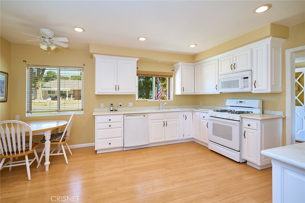 10370 Topeka Drive Porter Ranch, CA 91326 - Photo 15 of 33 a white kitchen with granite countertop a stove a sink a window and white stainless steel appliances