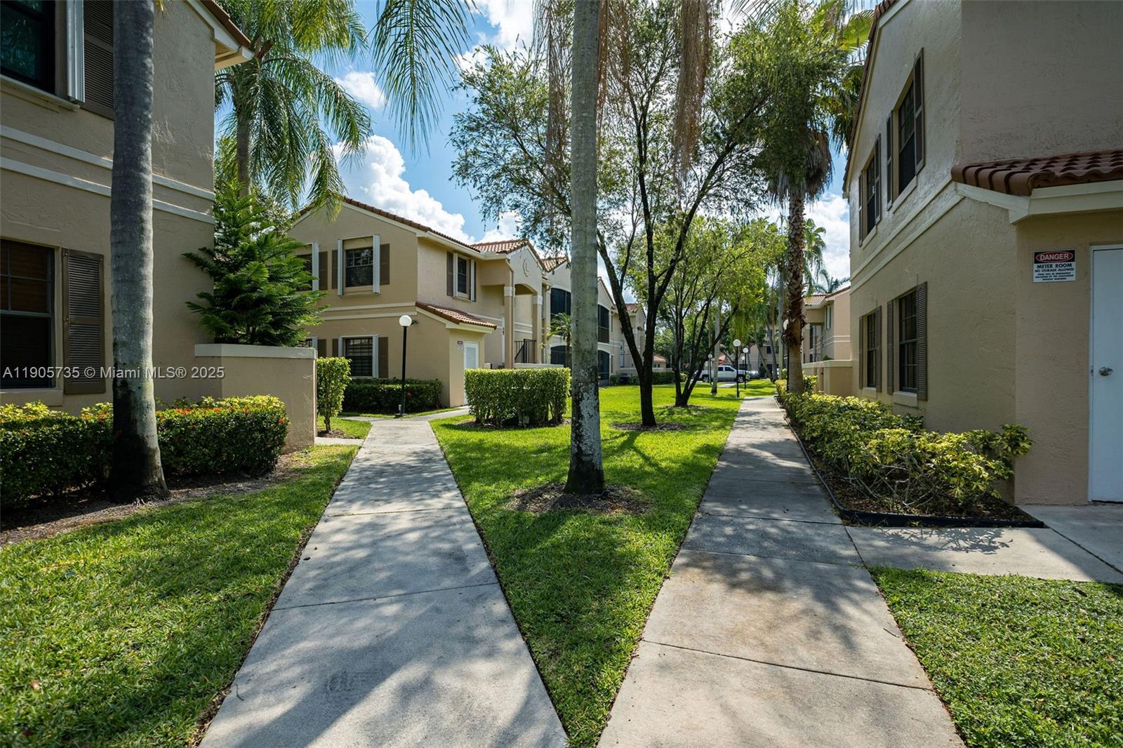 15865 Southwest 6th Place, Unit 201 Pembroke Pines, FL 33027 - Photo 47 of 80 a front view of a house with a yard and potted plants