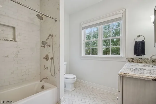 a bathroom with a granite countertop sink a toilet and shower