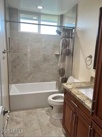 a bathroom with a granite countertop bathtub shower sink vanity and toilet