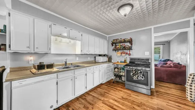 a large white kitchen with stainless steel appliances granite countertop a stove and cabinets