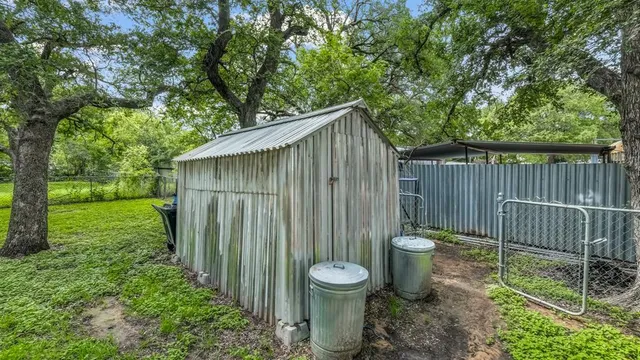 a view of a backyard with large trees and wooden fence