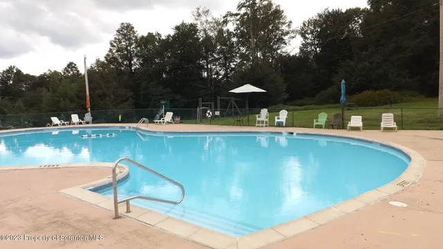 a view of a swimming pool with a table and chairs under an umbrella