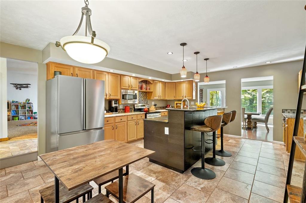 114 Will Scarlet Road Canonsburg, PA 15317 - Photo 7 of 14 a kitchen with granite countertop a refrigerator a stove a dining table and chairs with wooden floor
