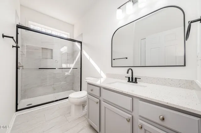 a bathroom with a granite countertop sink a toilet and a mirror