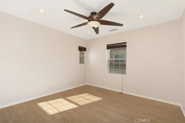 an empty room with wooden floor and ceiling fan
