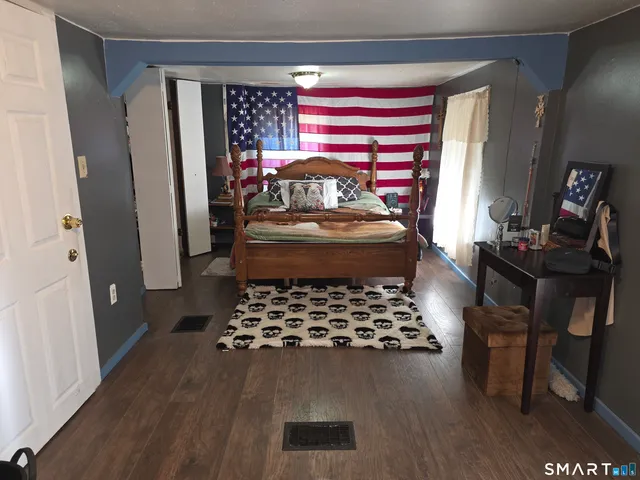 a bedroom with a bed and a dresser with wooden floor