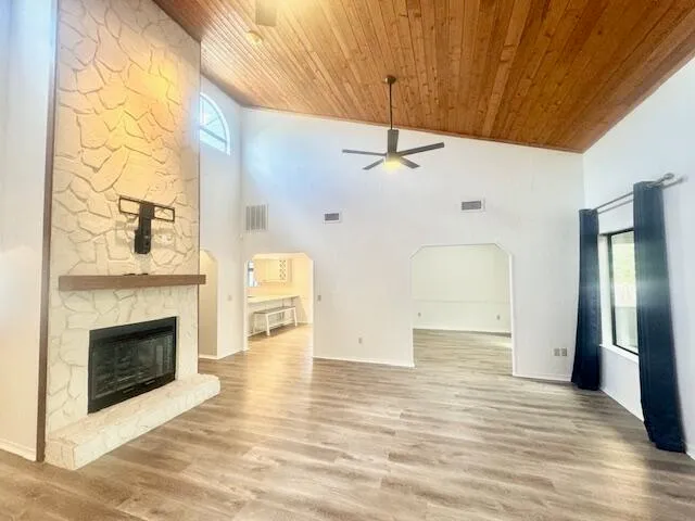 a view of an empty room with wooden floor a fireplace and a window
