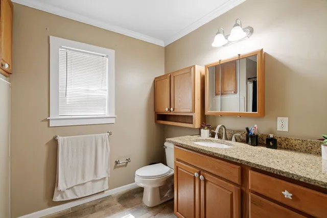 a bathroom with a granite countertop toilet sink and mirror