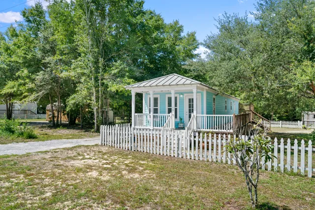 a view of a house with a small yard and a large tree