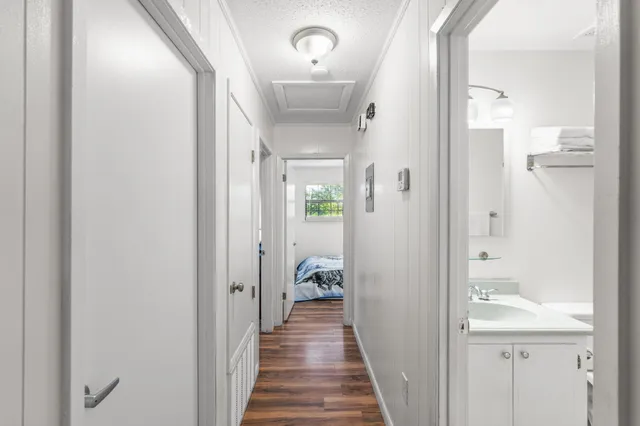 a view of a hallway with wooden floor and a bathroom