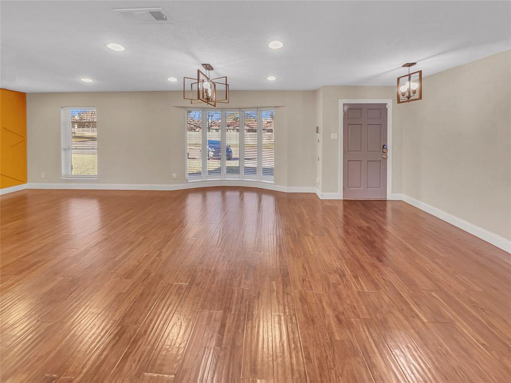 1736 Reynoldston Lane Dallas, TX 75232 - Photo 10 of 17 an empty room with wooden floor kitchen view and windows