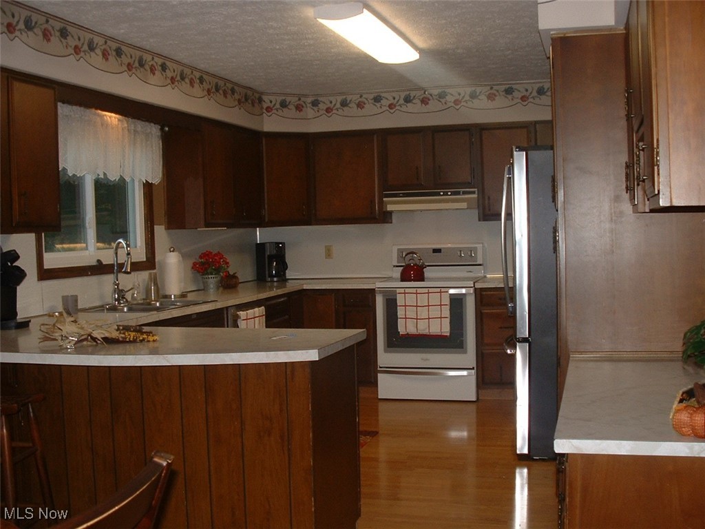Newer electric range and stainless steel refrigerator, spice cabinet, laminate flooring