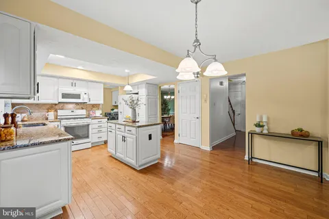 a kitchen with granite countertop white cabinets and white appliances
