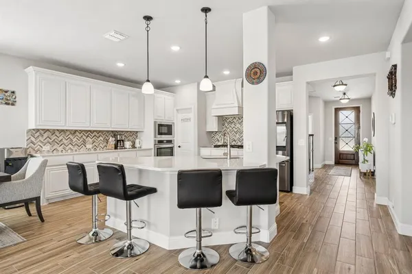 a kitchen with stainless steel appliances kitchen island granite countertop a table chairs and white cabinets