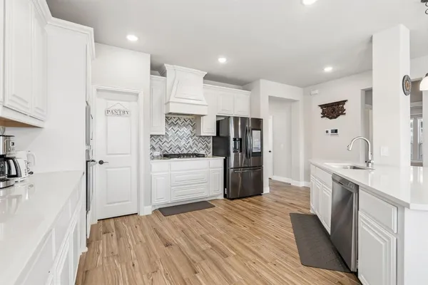 a large kitchen with a wooden floor and stainless steel appliances
