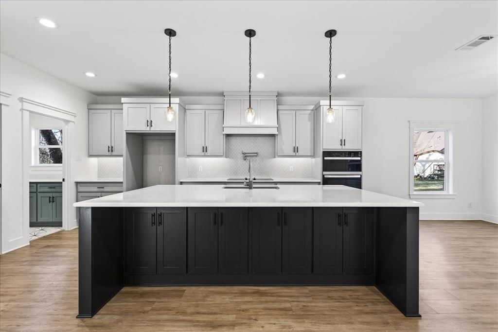 114 Castlewood Road Enchanted Oaks, TX 75156 - Photo 1 of 33 a kitchen with stainless steel appliances a sink a center island and a wooden floor