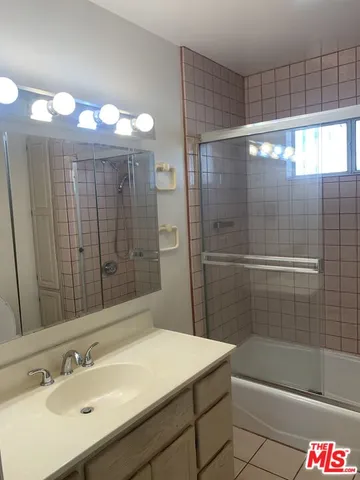 a bathroom with a shower sink vanity and mirror