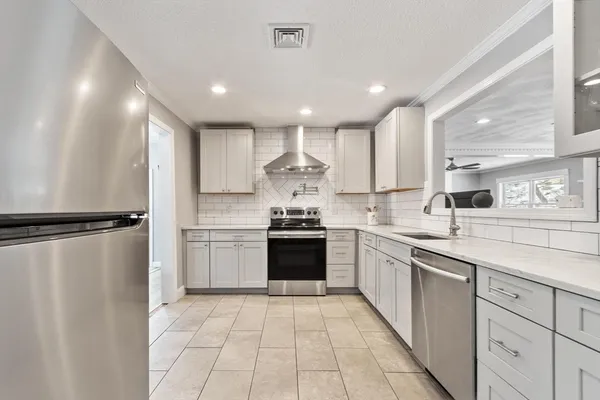 a large kitchen with a large counter top space a sink stainless steel appliances and cabinets