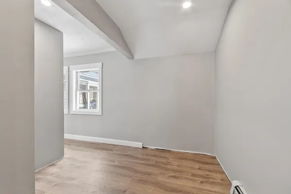 a view of an empty room with a window and wooden floor