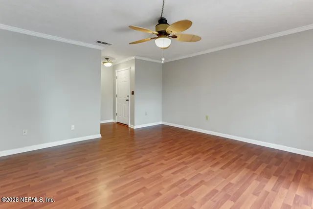 an empty room with wooden floor and chandelier fan
