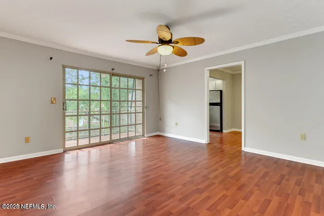 a view of an empty room with wooden floor and a window