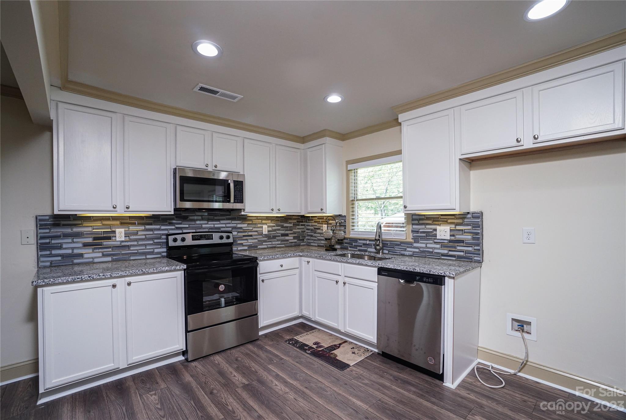 1302 Trinity Church Road Monroe, NC 28112 - Photo 3 of 37 a kitchen with stainless steel appliances granite countertop a stove top oven a sink and white cabinets