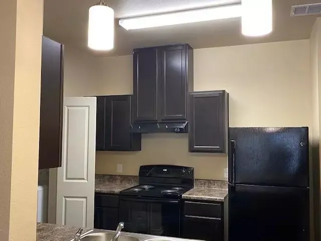 a kitchen with a refrigerator and a stove top oven