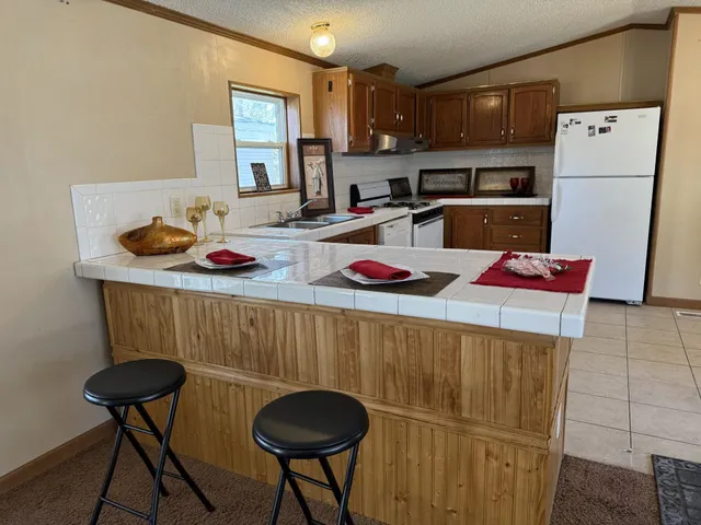 a kitchen with stainless steel appliances kitchen island granite countertop a sink refrigerator and cabinets
